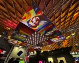 Installazioni artistiche colorate dominano il soffitto di una mir fiera, con volti stilizzati e il logo "Hikvision".