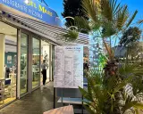 Osteria del Mare, ristorante pizzeria a Rimini centro, con menù esposto e tavoli all'esterno. Palme illuminate con lucine.