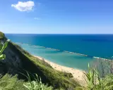 Vista panoramica della spiaggia di Fiorenzuola di Focara, con mare azzurro e scogliera verdeggiante.