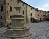 Piazza con fontana in pietra, circondata da edifici storici. Un angolo di pace nei borghi vicino Cattolica.