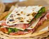 Piadina romagnola con prosciutto crudo e rucola, un'ottima opzione per chi cerca dove mangiare a Rimini.