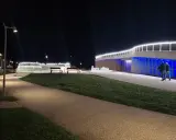 Passeggiata serale a **Piazzale Kennedy Rimini**, con fontane luminose e architettura moderna illuminata.