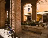 Sotto gli archi di mattoni rossi, un tempo la vecchia pescheria, ora un fiorista espone i suoi colori. Una bicicletta blu riposa sul selciato.