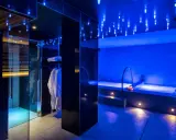 Interni di un centro benessere a Riccione con docce emozionali, vasca idromassaggio e accappatoi bianchi, illuminati da luci blu soffuse.