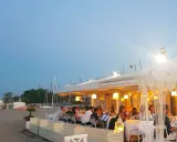 Serata in uno dei ristoranti della Riviera Romagnola, con tavoli apparecchiati sulla sabbia e luci soffuse.
