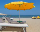 Spiagge di Rimini con lettini, ombrellone giallo e pedalò pronti per l'estate.