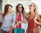 Tre amiche ridono felici con borse della spesa, dopo un pomeriggio di shopping nel cesenatico centro negozi.