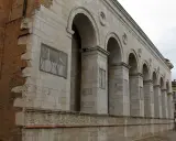 Archi maestosi e decorazioni in pietra della chiesa San Francesco a Rimini, con un muro in mattoni a vista che racconta la sua storia.