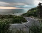 Strada tortuosa sul Monte San Bartolo con vista sul mare Adriatico al tramonto.