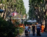 Passeggiata nel centro di Bellaria, con giostra, alberi maestosi e famiglie con passeggini.