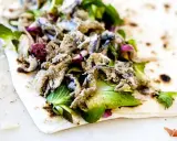 Sardoncini al testo su piadina con insalata fresca e cipolla rossa. Un sapore di mare e terra.