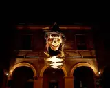 Una strega spaventosa con un cappello nero e una sfera luminosa in mano, illuminata nella notte. Sembra la protagonista de la notte delle streghe.