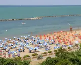 Spiaggia affollata con ombrelloni colorati, lettini e bagnanti. Perfetta idea per sapere dove andare al mare in Emilia Romagna.