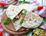 Piadina, piatto tipico di Rimini, farcita con prosciutto e rucola, servita con guacamole e verdure fresche.