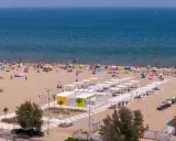 Una vivace spiaggia libera a Rimini, con bagnanti che si godono il sole e il mare sotto ombrelloni colorati.