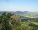 Un gruppo di escursionisti fa trekking su un crinale roccioso con vista panoramica sulle colline verdi, un'avventura indimenticabile vicino a Rimini.