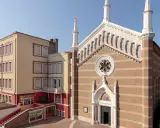 Facciata di una chiesa a Rimini con campanile e edificio adiacente.