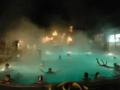 Persone rilassate nelle piscine delle terme riviera romagnola, con luci natalizie e vapore che creano un'atmosfera magica.