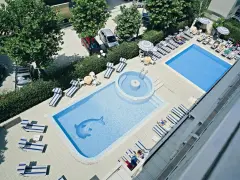 Piscina con sdraio e ombrelloni, un delfino azzurro decora il fondo. Le recensioni per l'hotel Tridentum Cesenatico sembrano positive.