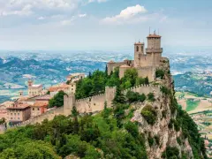 Torri medievali su un monte roccioso, con vista panoramica sulla campagna circostante, un paesaggio che ricorda la vicinanza di San Marino a Rimini.
