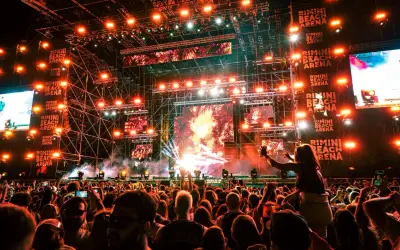 Folla in delirio al Rimini Beach Arena, luci psichedeliche e musica pulsante per un evento indimenticabile.