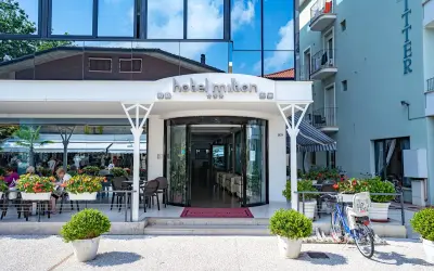 Ingresso accogliente dell'Hotel Milton Valverde con tavolini all'aperto e fiori colorati. Biciclette parcheggiate, pronte per esplorare.