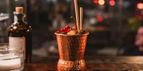 Cocktail in rame, decorato con frutti rossi e cannella, perfetto per un aperitivo Milano Marittima.