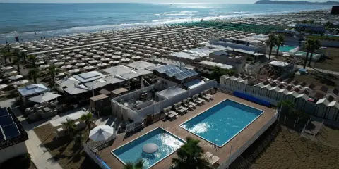 Vista aerea della spiaggia Le Palme Riccione con ombrelloni, piscine e cabine.