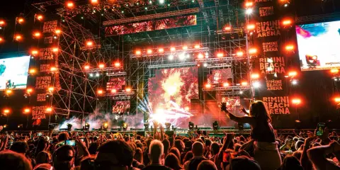 Folla in delirio al Rimini Beach Arena, luci psichedeliche e musica pulsante per un evento indimenticabile.