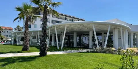 Palme e prato verde davanti a un moderno ristorante a Bellaria Igea, con un edificio bianco sullo sfondo.