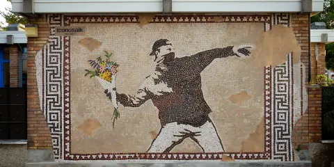 IconosaiK project: street art a Ravenna con un mosaico che raffigura un uomo lancia fiori, un messaggio di pace.