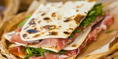 Piadina romagnola con prosciutto crudo e rucola, un'ottima opzione per chi cerca dove mangiare a Rimini.