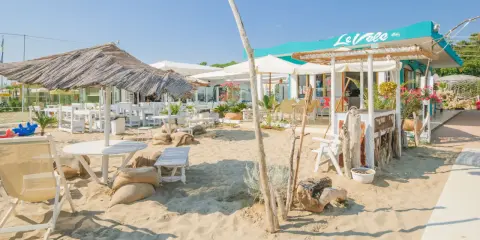 Un angolo di cervia strand con tavoli, sedie e ombrelloni di paglia, pronto ad accogliere i bagnanti.
