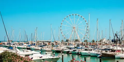 Porto di Rimini con ruota panoramica e barche a vela. Un luogo dove nascono tante storie di mare.