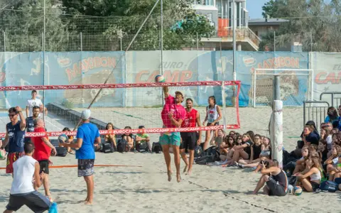 Partita di camp volley Cesenatico: un giocatore salta per colpire la palla mentre gli spettatori osservano.