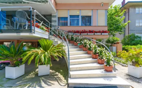 L'ingresso fiorito del hotel dell'amarissimo, con scale bianche ornate da piante e fiori, invita ad entrare.