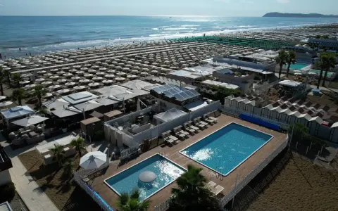 Vista aerea della spiaggia Le Palme Riccione con ombrelloni, piscine e cabine.