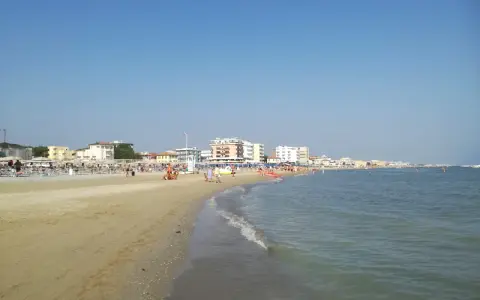 Spiaggia affollata a Viserbella mare, con ombrelloni, lettini e persone che si godono il sole e il mare azzurro sotto un cielo limpido.