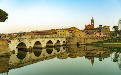 Ponte di Tiberio a Rimini, un luogo che evoca la magia di Fellini, con le sue arcate che si specchiano nell'acqua calma.