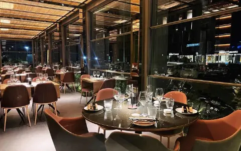 Interni eleganti del miglior ristorante di Rimini, con tavoli apparecchiati e vista notturna sulla città.