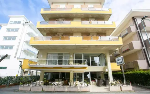 Hotel Ischia a Rimini Marebello, con le sue terrazze gialle e le finestre luminose, pronto ad accogliere i suoi ospiti per una vacanza al mare.
