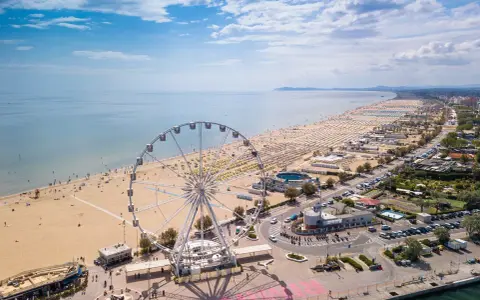 Vista aerea delle spiagge romagna con ruota panoramica, ombrelloni e mare azzurro.