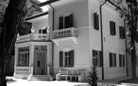 Villa Franceschi a Riccione, un'elegante dimora con balconi e un ingresso accogliente, circondata da alberi e un giardino curato.