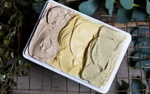 Tre gusti di gelato artigianale, tra cui la romana, in una vaschetta bianca.