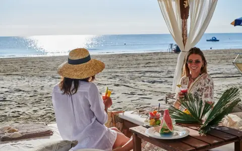 Due donne sorseggiano cocktail in un bagno Jacarè a Cervia, godendosi la spiaggia e il mare.