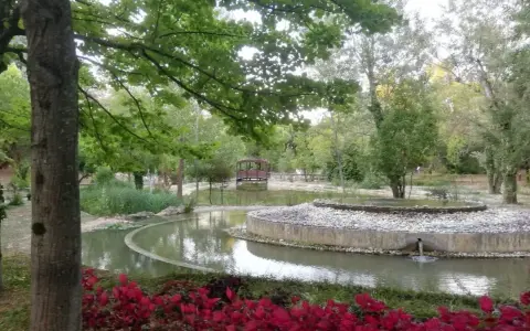 Un laghetto con un ponticello in legno e aiuole fiorite nel Parco della Resistenza a Riccione.