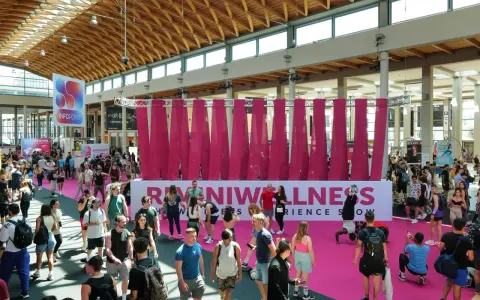 Folla animata a Rimini Wellness, un evento dedicato al benessere e al fitness. Persone di ogni età passeggiano tra gli stand e le aree espositive.