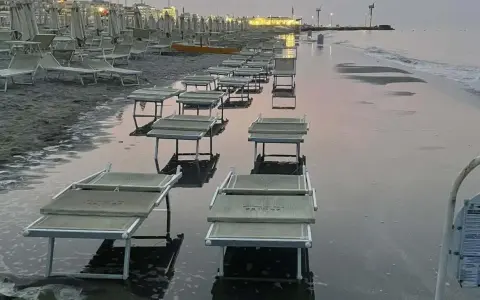 Lettini da spiaggia sommersi dall'acqua a Riccione, con la bassa marea che ha lasciato il segno.