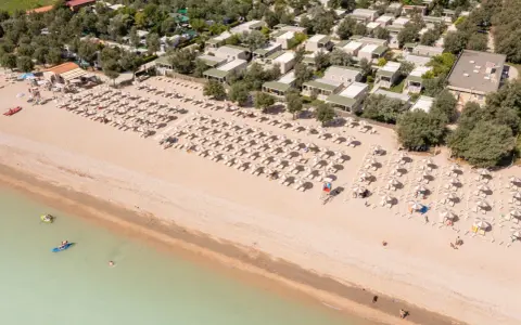 Domenica di sole sulla spiaggia di Rivazzurra, con ombrelloni, lettini e bagnanti che si godono il mare.