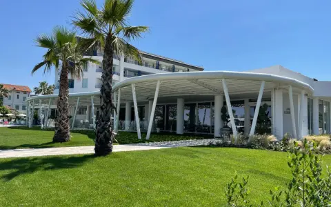 Palme e prato verde davanti a un moderno ristorante a Bellaria Igea, con un edificio bianco sullo sfondo.